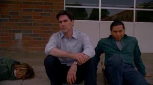 Agent Hotchner and local officer sitting beside an unsub waiting to be picked up